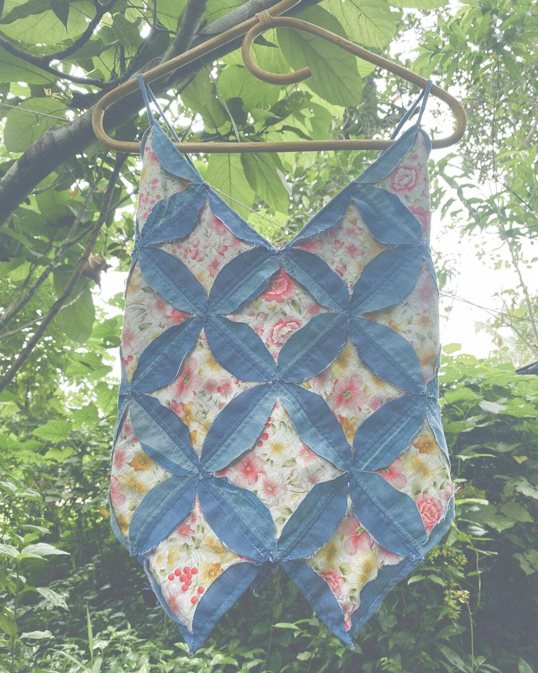 Genie Vest Patchwork vest displayed on a bamboo hanger outdoors.