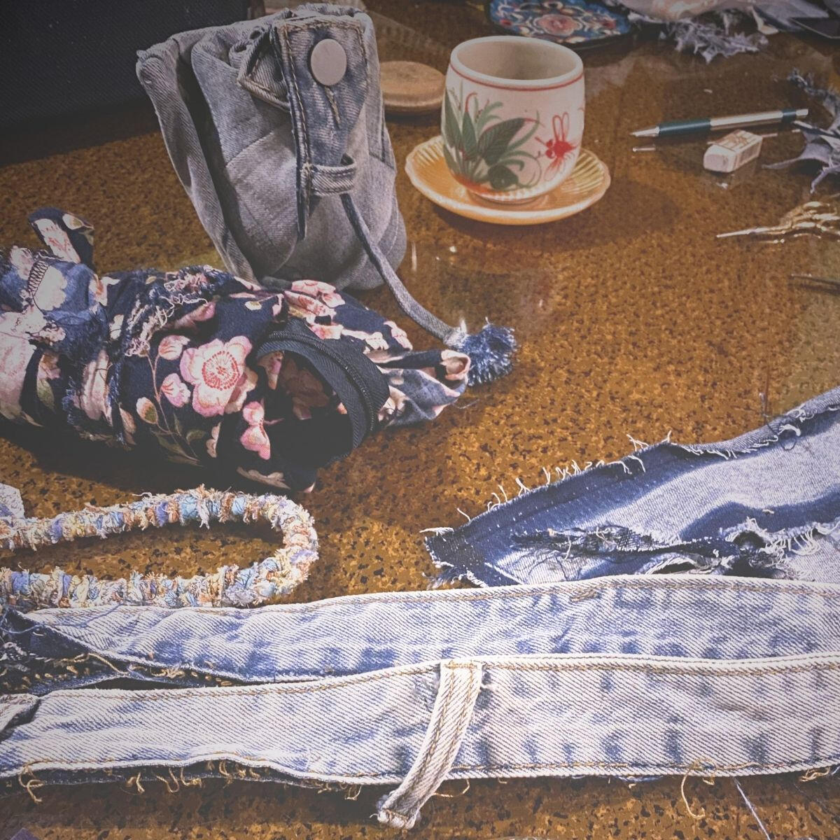 Genie Material Disassembled denim garment pieces and folded tote bag on a work table.